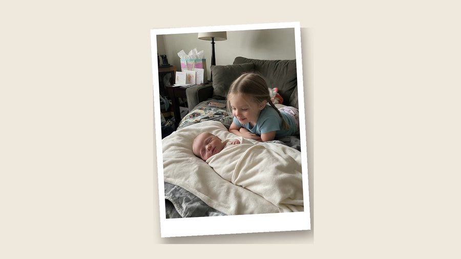 Geüploade foto: grote zus kijkt naar haar pasgeboren broertje, als polaroid